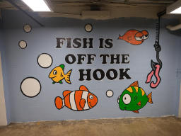 Depicts four fish, and a worm on a hook. Text says 
