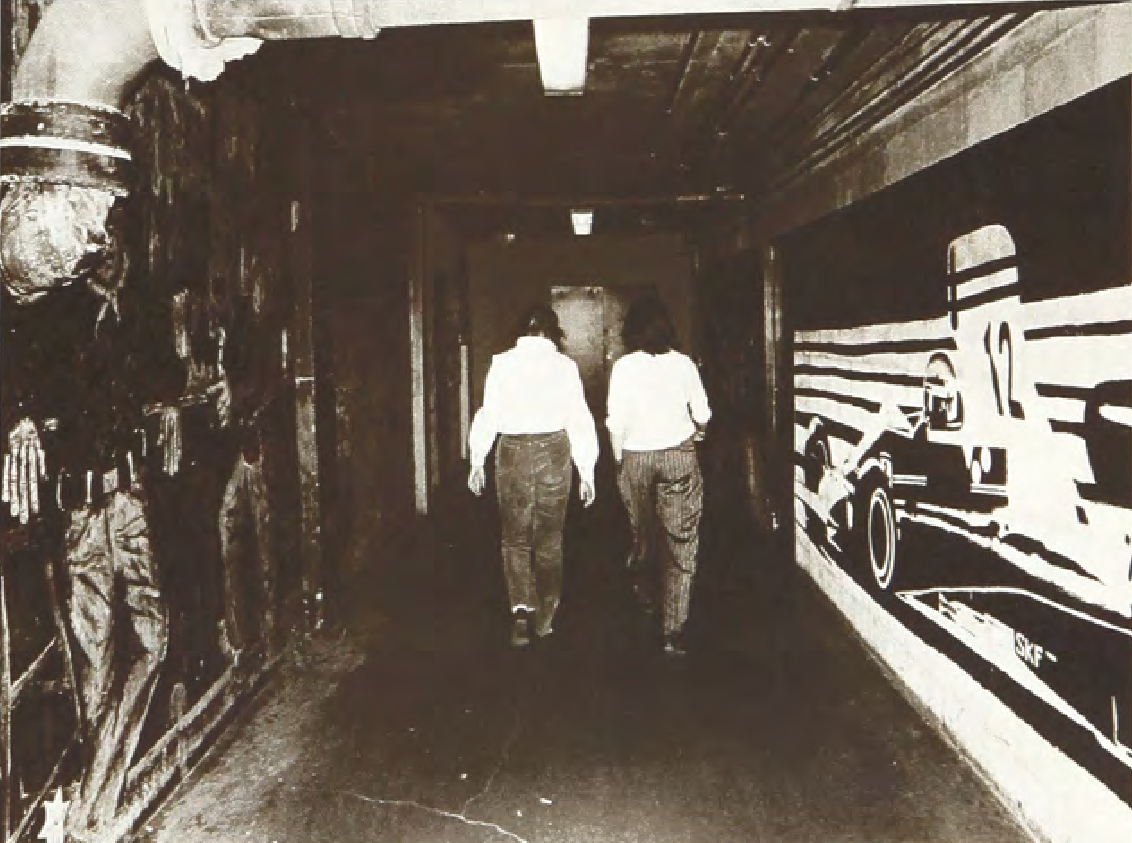 Photo of a dimly lit tunnel with two students walking through.